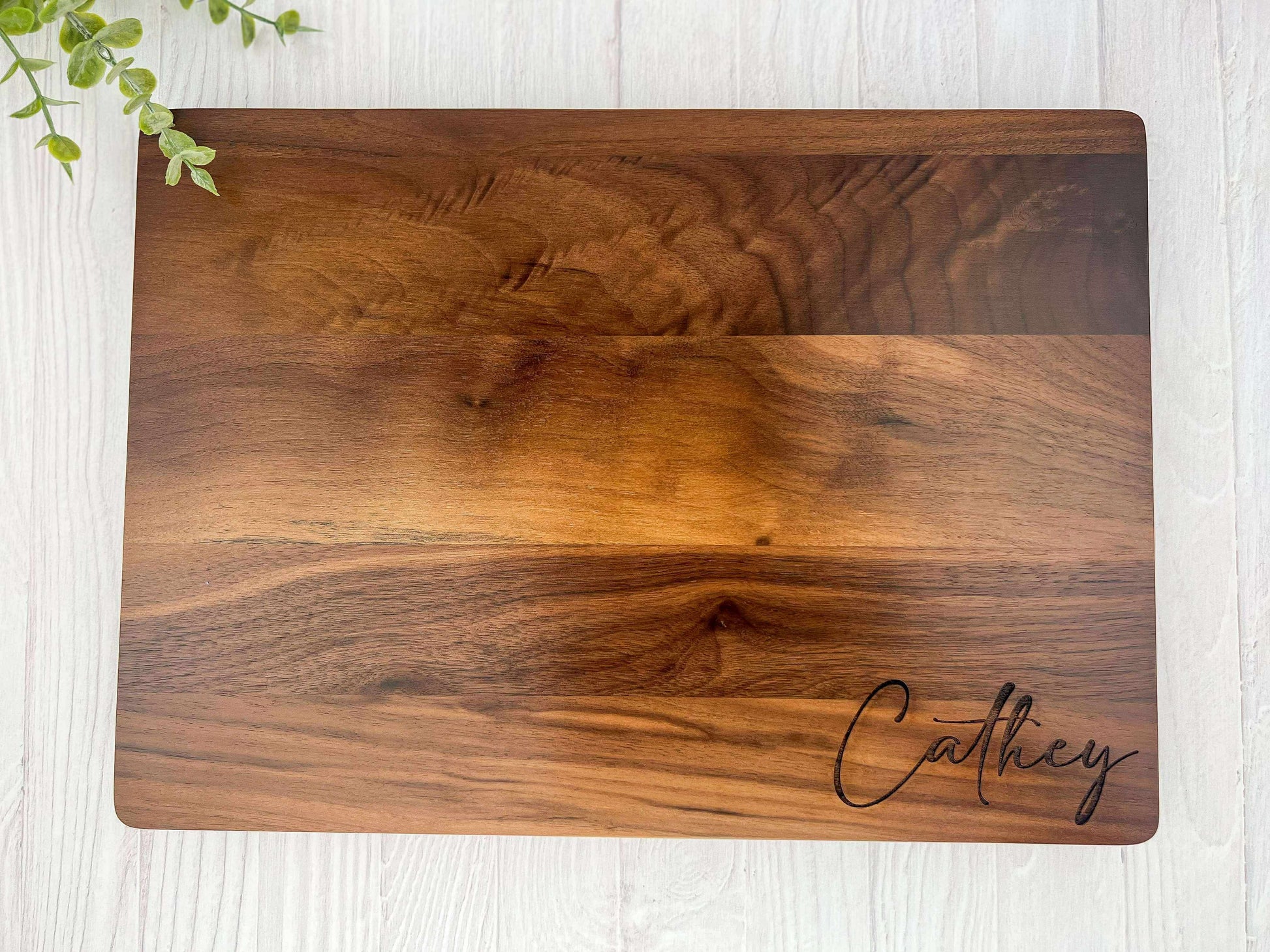 Wooden cutting board with 'Cathey' engraving on a light wooden surface.