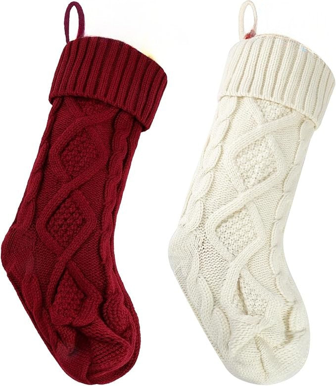 Two Christmas stockings with personalized name tags on a festive background with ornaments and greenery.