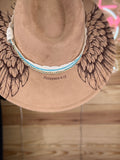 Brown hat with wing design and 'Philippians 4:13' text on a wooden surface.