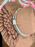Brown hat with wing designs and a white teal and gold chain hat band