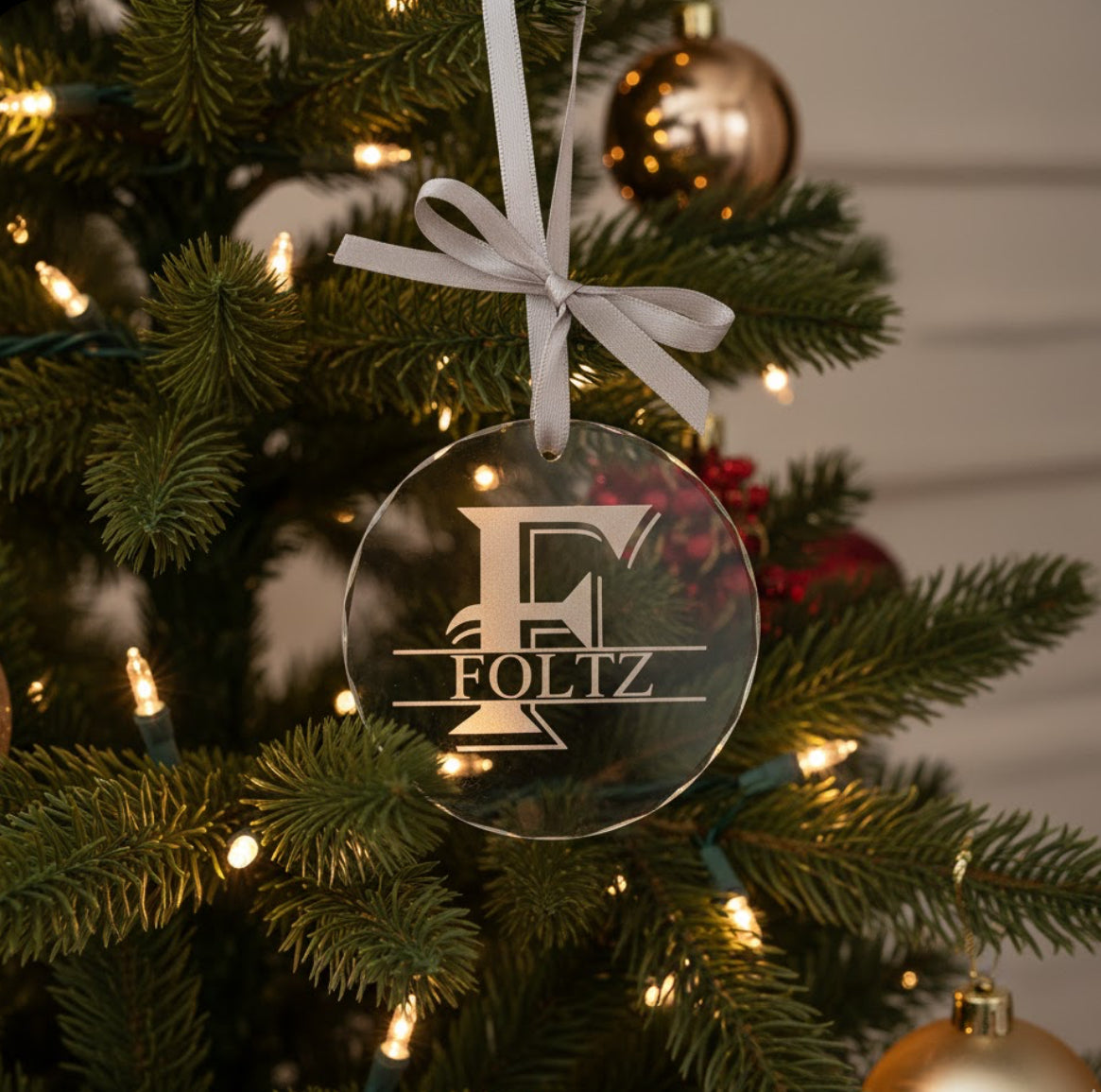 Crystal ornament with 'Foltz' logo on a decorated Christmas tree