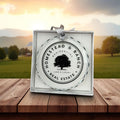 Ornament with 'Homestead & Ranch Real Estate' on a wooden surface with a scenic background.