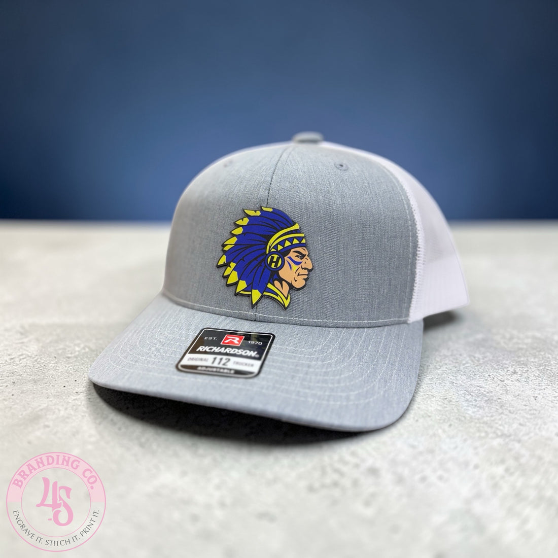 Gray and white cap with a logo on a textured surface and blue background